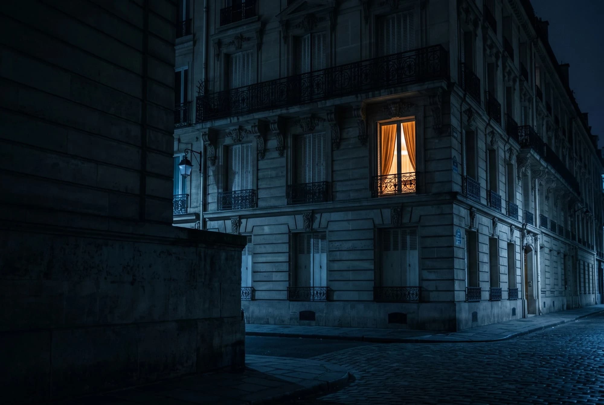 Une seule fenêtre encore éclairée dans un immeuble, tard le soir