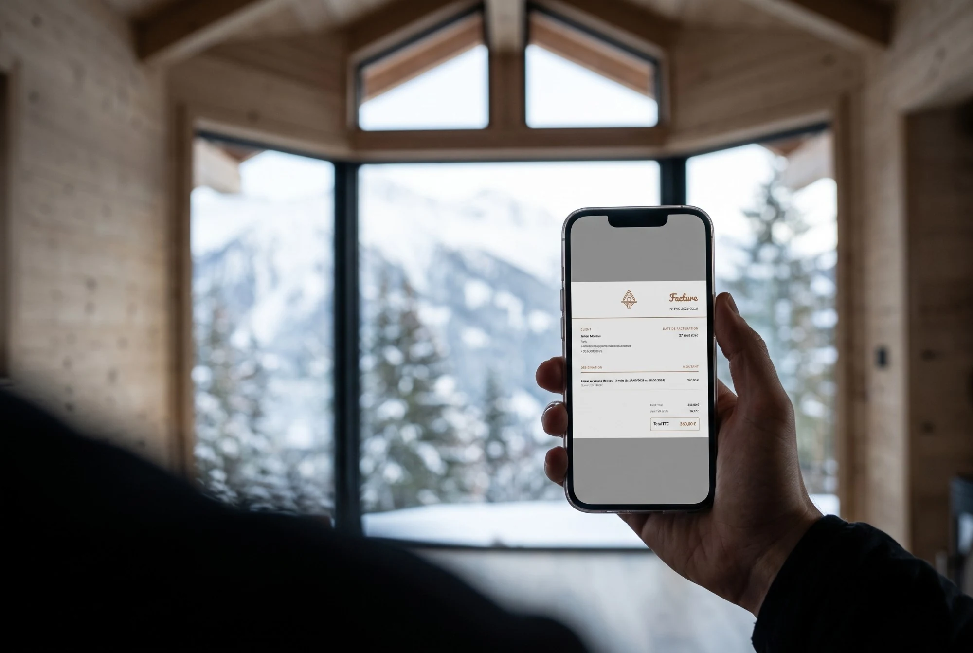 Un voyageur consulte sa facture sur son téléphone, depuis un chalet